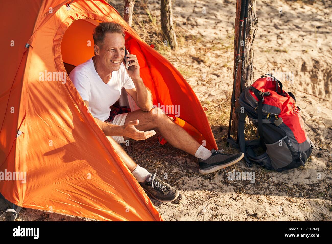 Joyful man talking on smartphone in tent in nature Stock Photo