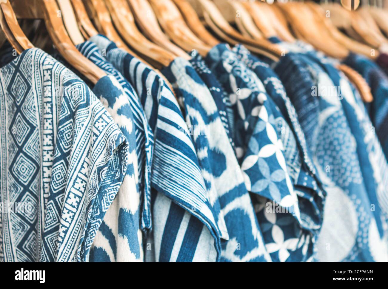 Selective focus tie dye shirts in blue white clothing hanging on rack. Stock Photo