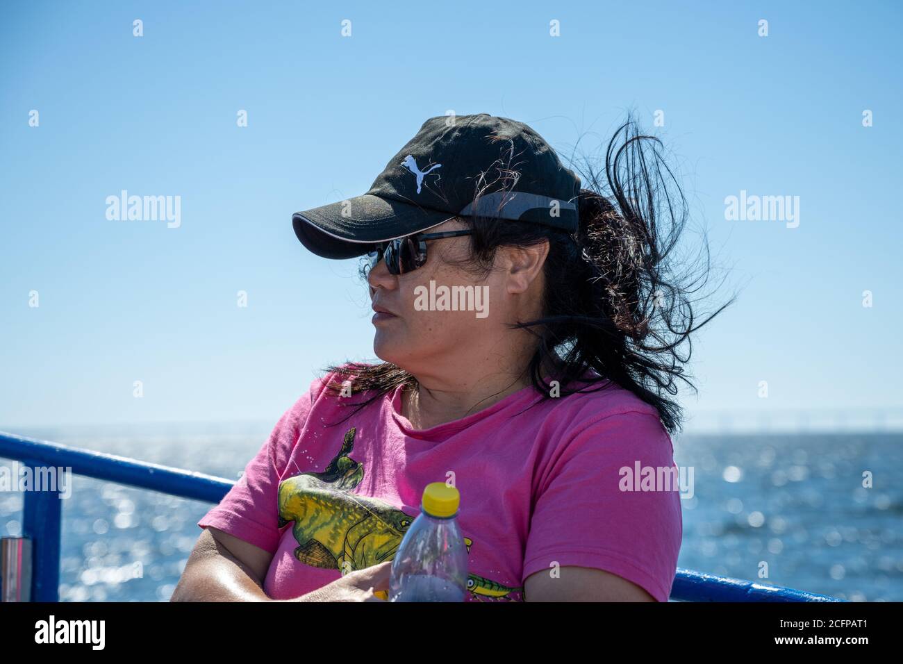 Malmo, Sweden - August 6, 2020: A middle-aged Asian woman on a boat trip a hot summer day. Bright blue sky and ocean in the background Stock Photo
