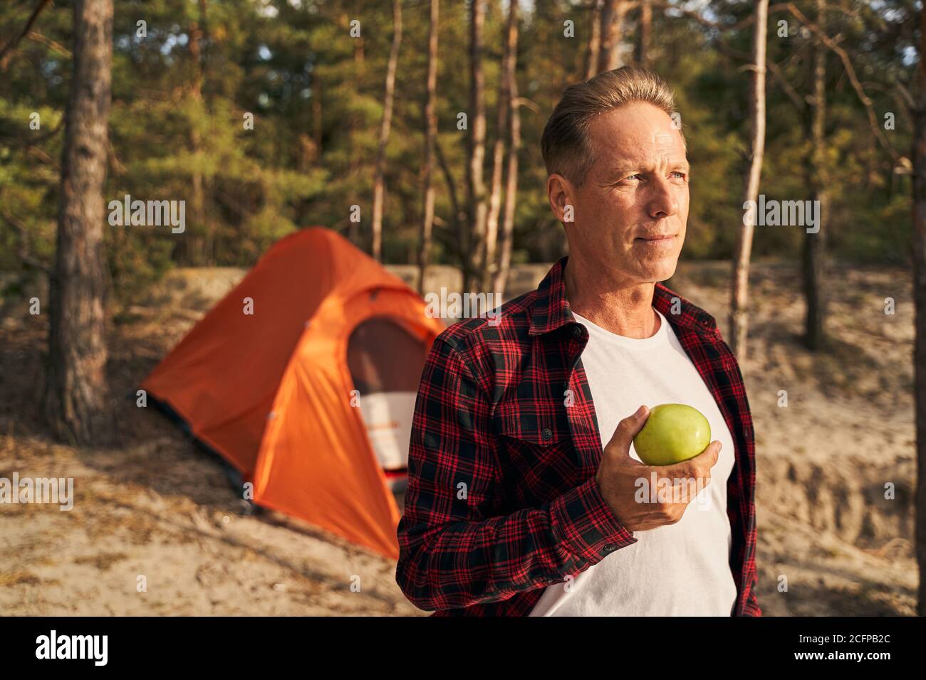 Man eating fresh fruit while going camping Stock Photo