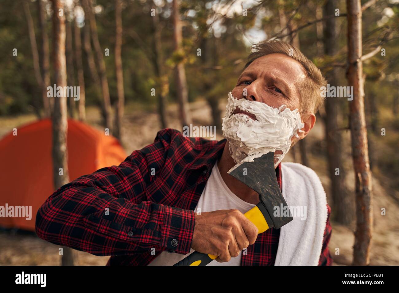 Man using hatchet for shaving in nature Stock Photo