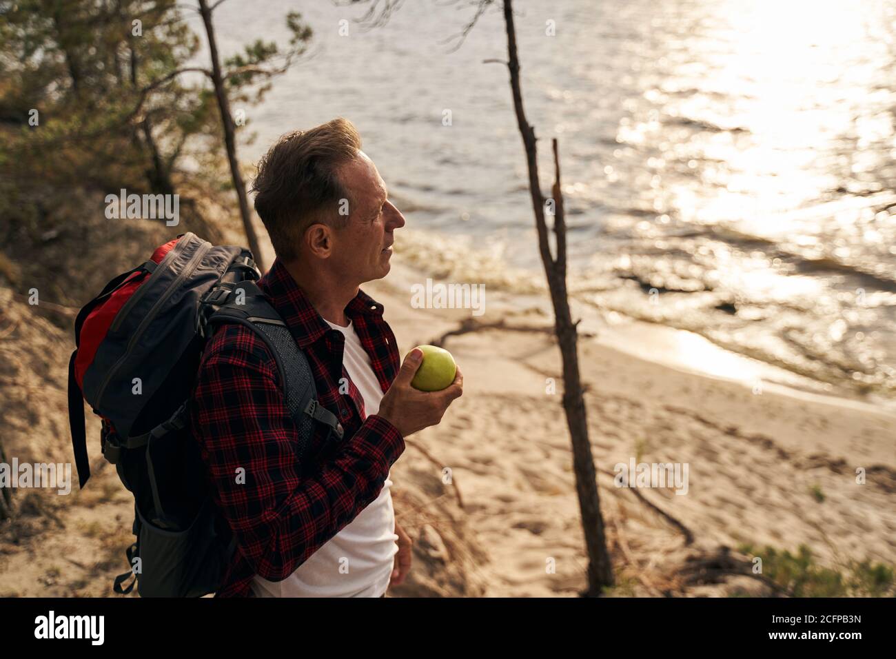 Man with apple going hiking near sea shore Stock Photo