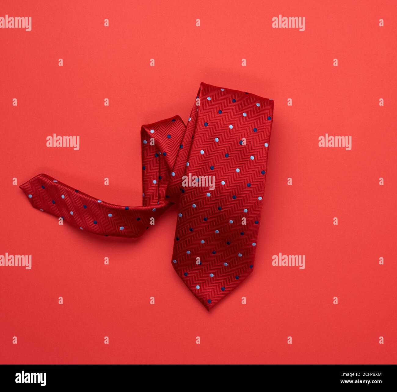 twisted silk red tie on red background, top view Stock Photo