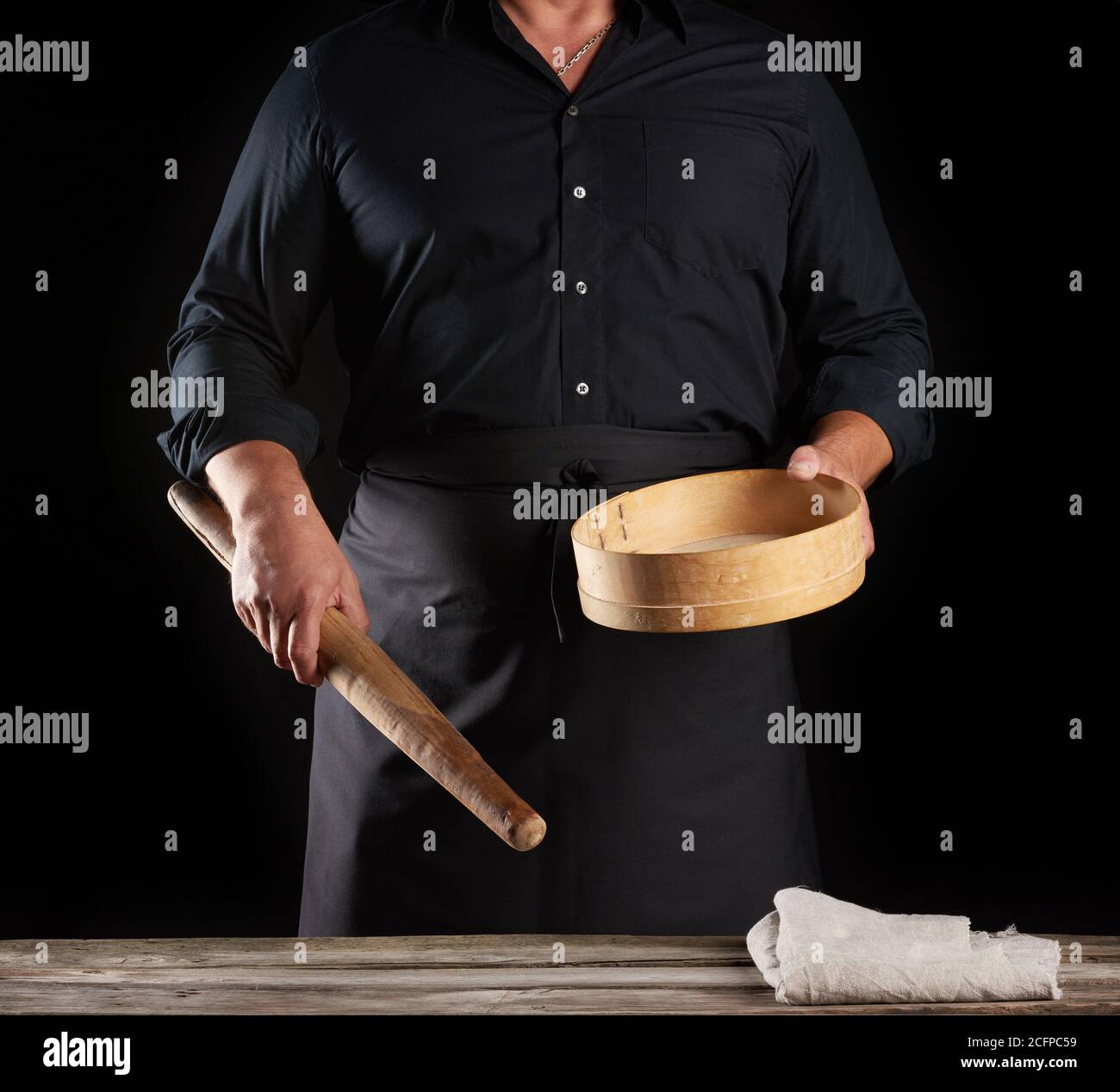 man in black uniform holding empty vintage round wooden sieve for ...