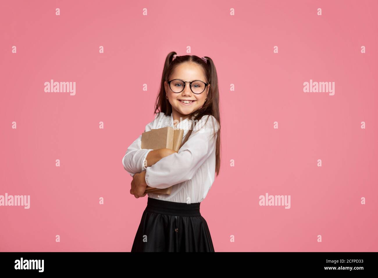 I love school. Smiling girl with in glasses hugs books and looks at camera Stock Photo