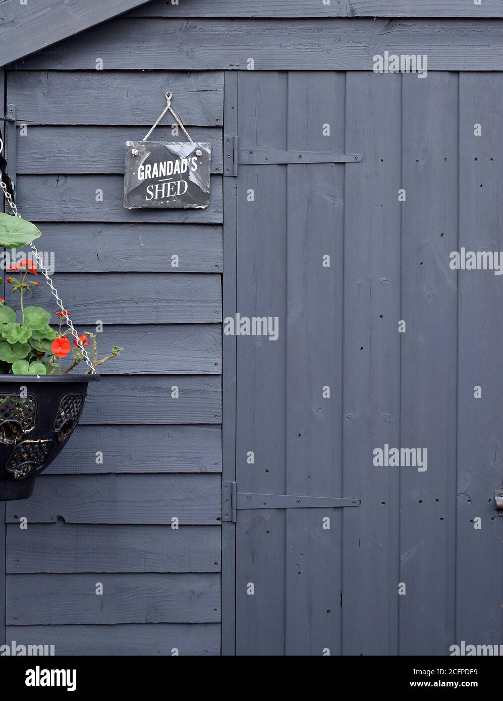 Grandad's garden shed with sign and geraniums in hanging basket depicting home and family, love and belonging. Stock Photo