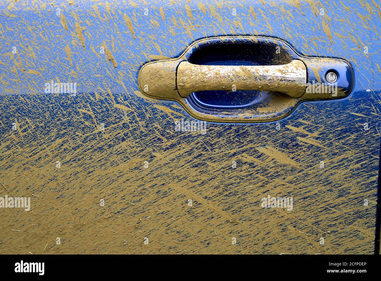 Silver car door handle on a blue automobile covered in mud spatter Stock Photo
