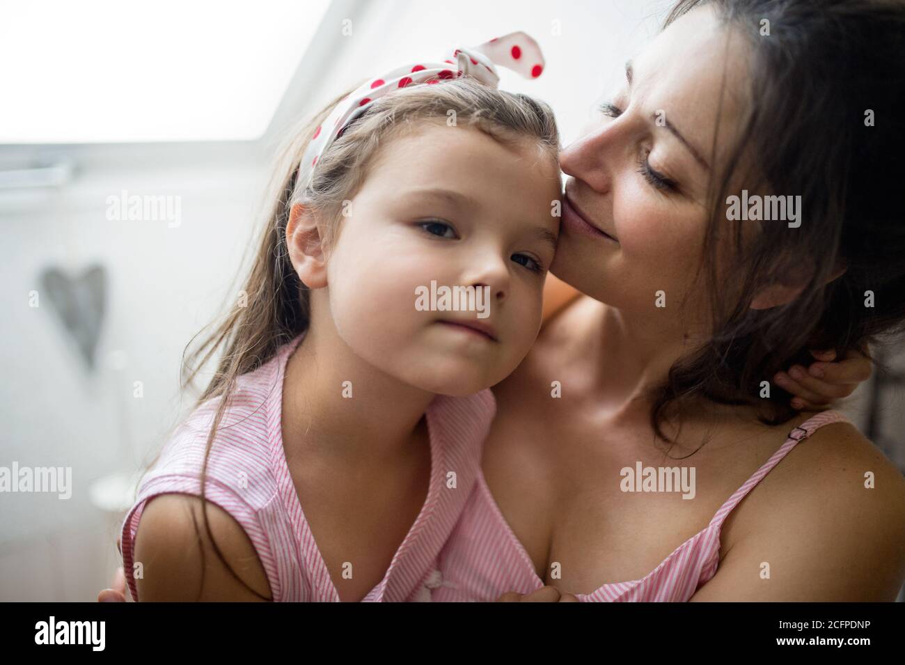 Mother and small daughter indoors at home, hugging. Stock Photo