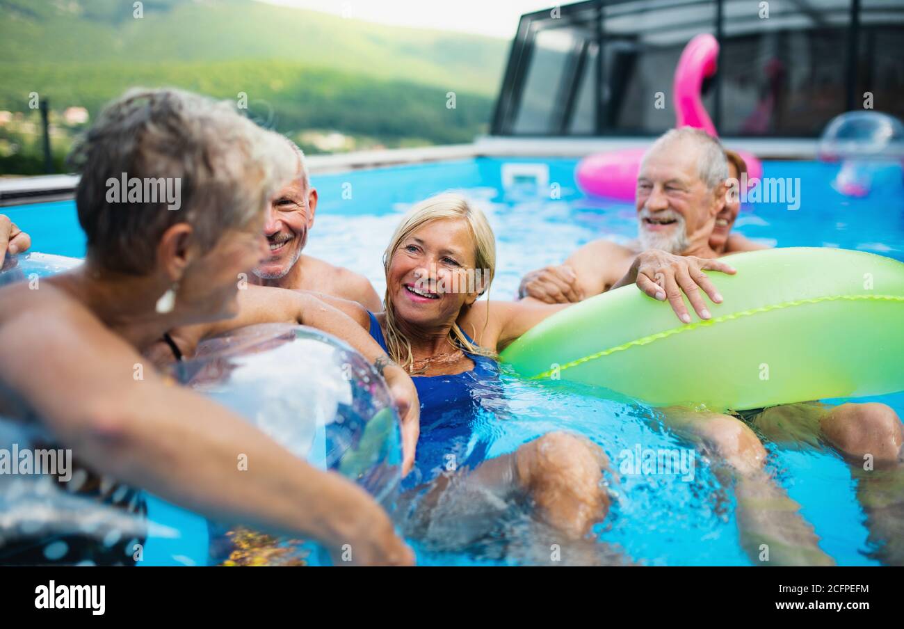 Senior Pool Fun Group of cheerful seniors in swimming pool outdoors in backyard ...