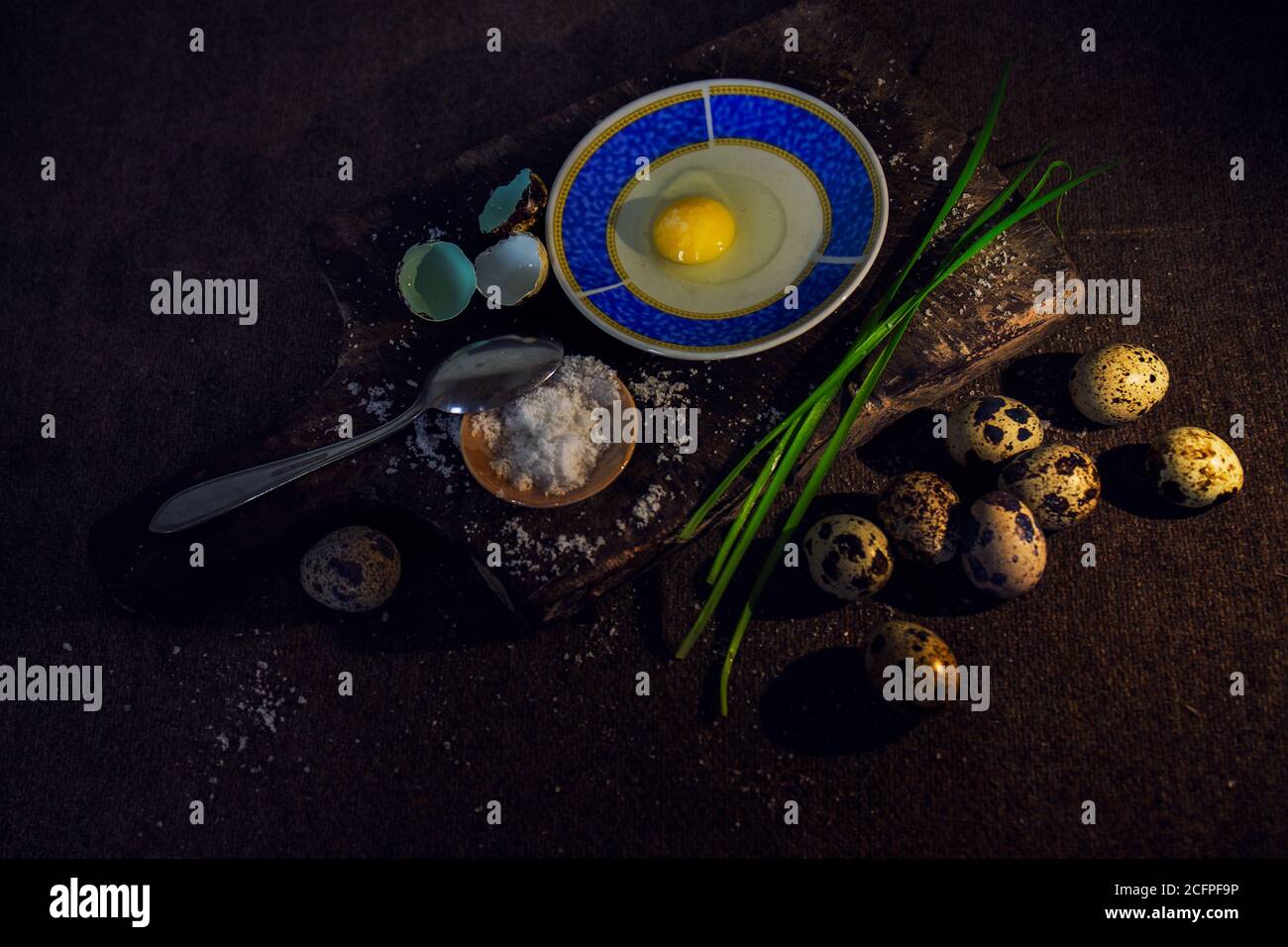 Closeup of quail eggs beside a wooden board with condiments for cooking Stock Photo