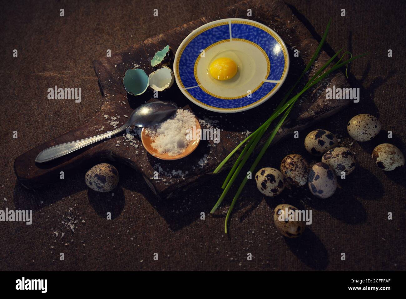 Closeup of quail eggs beside a wooden board with condiments for cooking Stock Photo