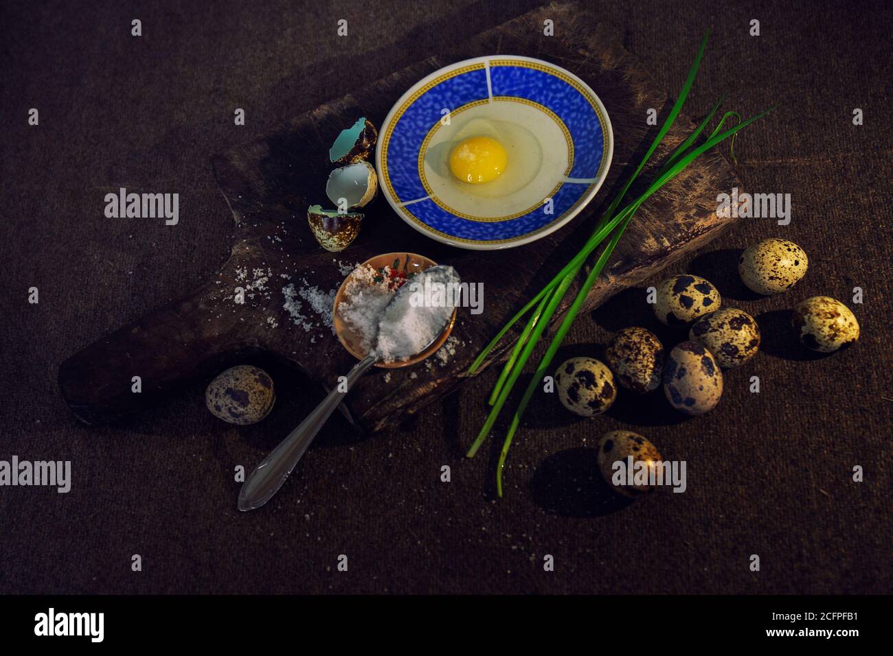 Closeup of quail eggs beside a wooden board with condiments for cooking Stock Photo