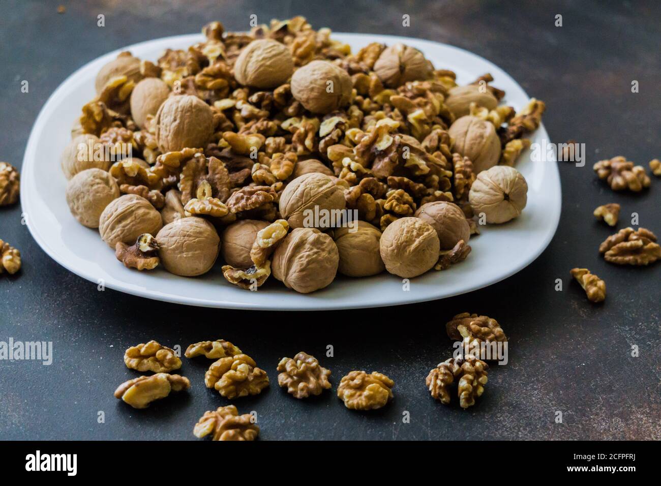 Walnuts peeled and in shells on a table in a plate Stock Photo