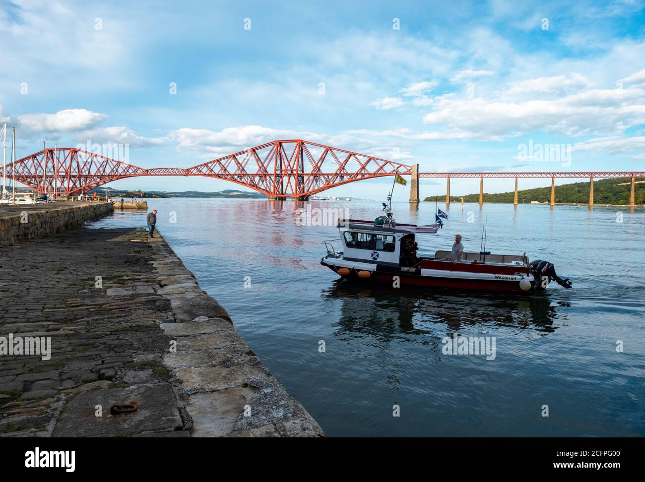 The Ferry Flyer sails into South Queensferry harbour, with the Forth Rail Bridge behind. Stock Photo