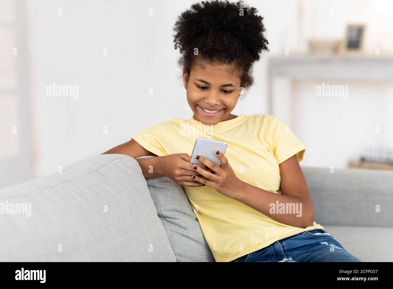 Happy Teen Girl Using Phone Sitting On Sofa At Home Stock Photo - Alamy