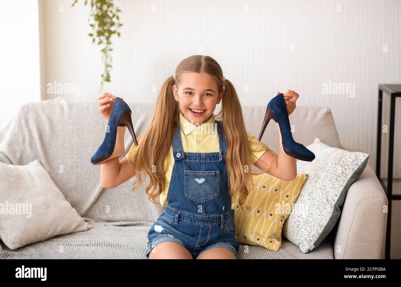 Little girl holding pair of high heels shoes Stock Photo