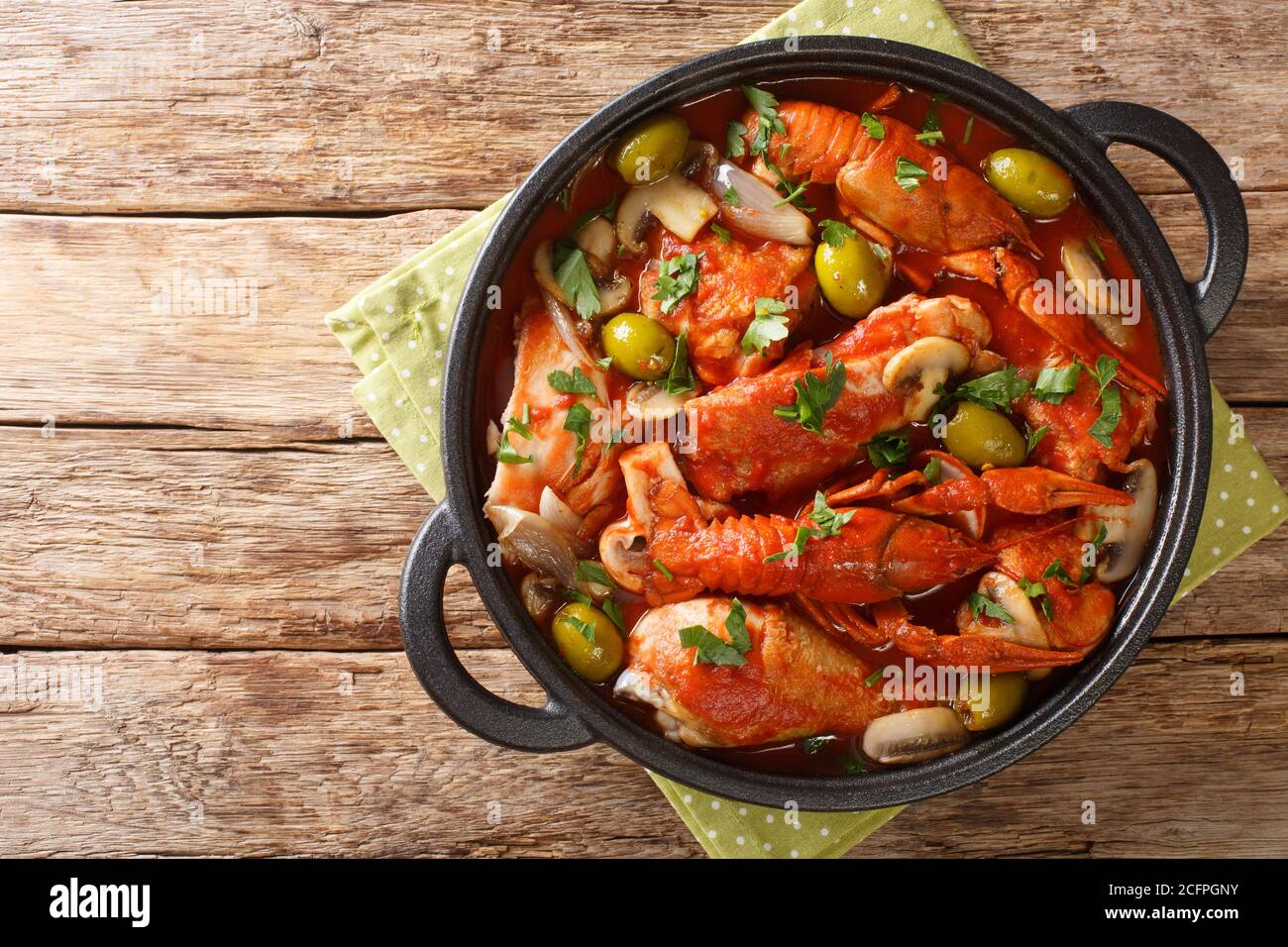 One pot Chicken Marengo with crayfish, mushrooms, olives, garlic, tomatoes and shallots close-up in a saucepan on the table. horizontal top view from Stock Photo