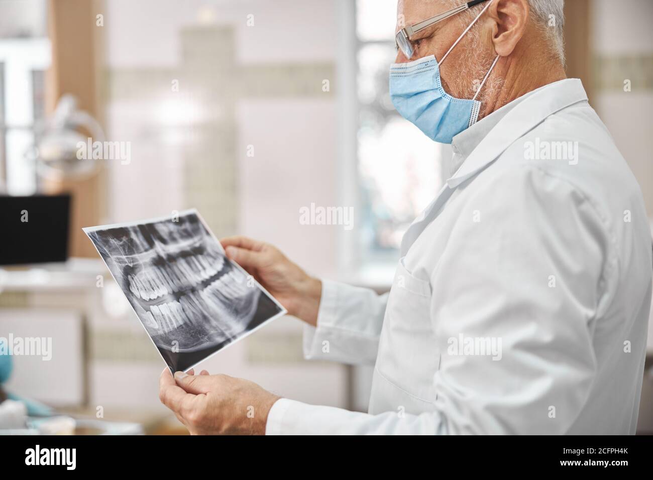 Experienced elderly dentist looking a dental radiogram Stock Photo