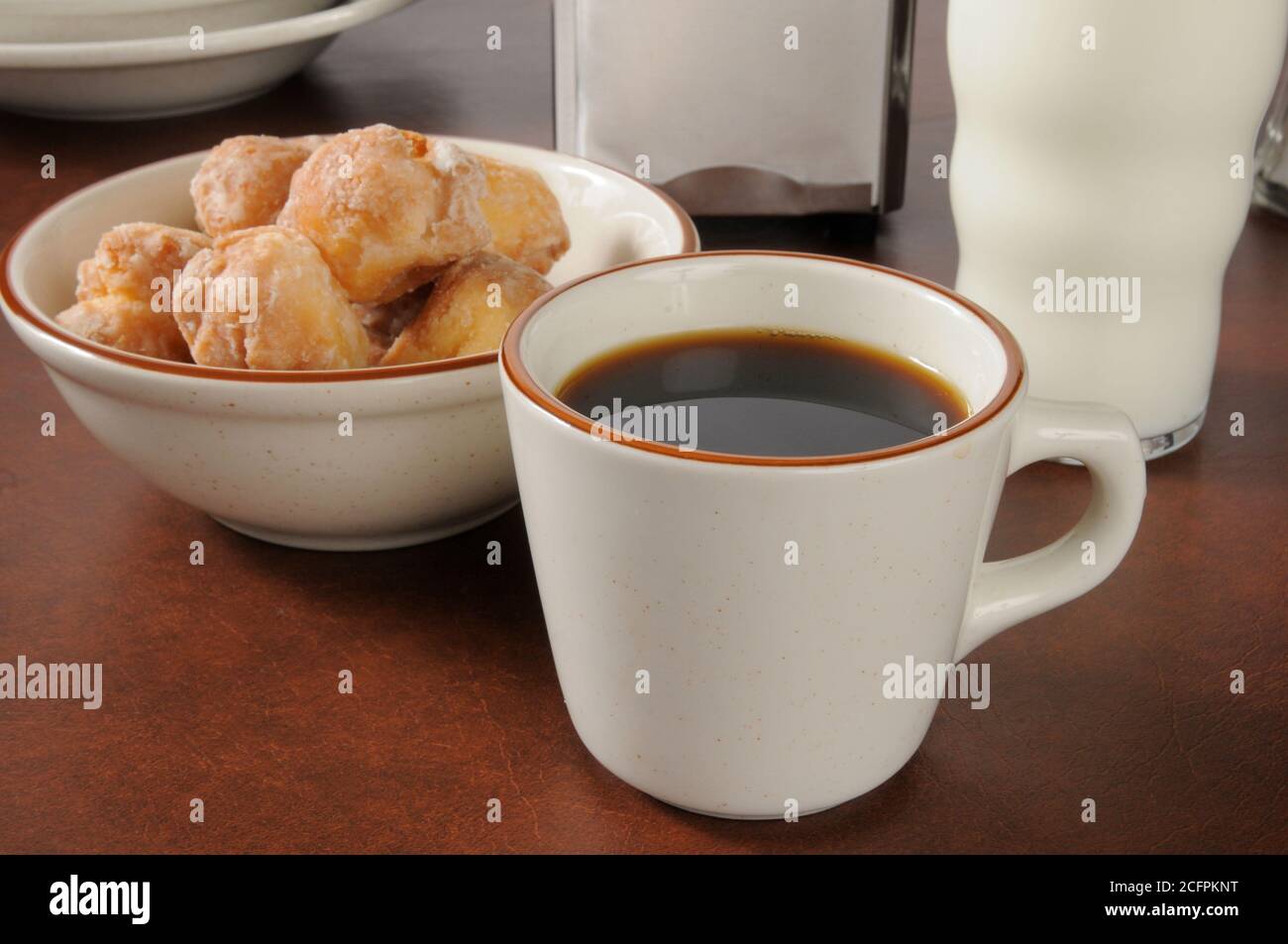 A cup of coffee with a bowl of donut holes Stock Photo