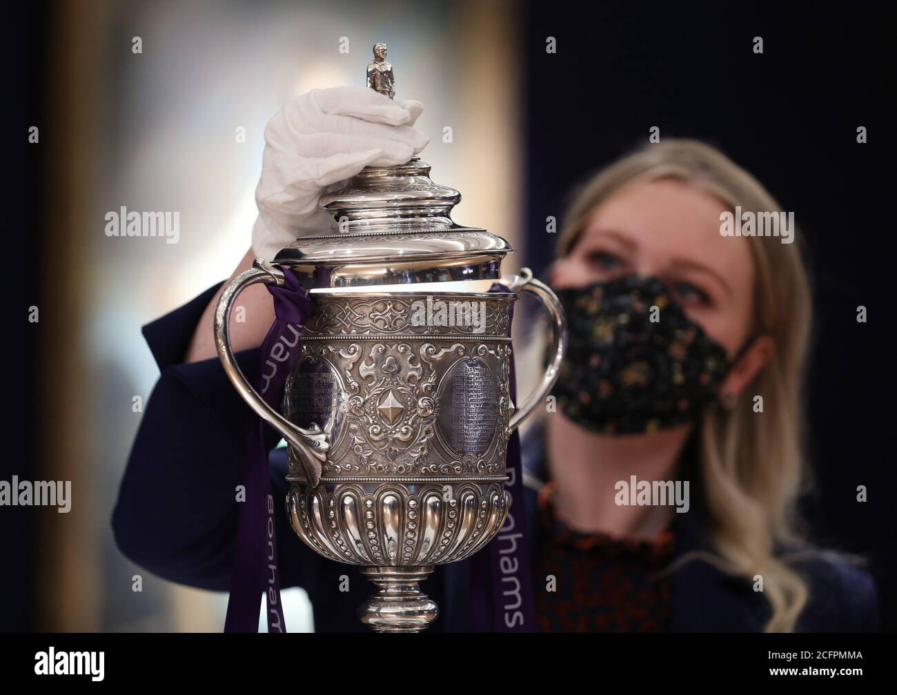 Laurel Kemp of Bonhams with the oldest surviving FA Cup trophy during a preview of the Sporting Trophies Sale at which will take place as Bonhams New Bond Street saleroom on September 29. The silver two-handled cup, estimated at GBP 700,000 -900,000, was made by Vaughton and Sons of Birmingham in 1896, and was presented to the FA Cup winning teams between 1896 and 1910, including Manchester United, Manchester City, Everton, Newcastle United and Tottenham Hotspur. Stock Photo