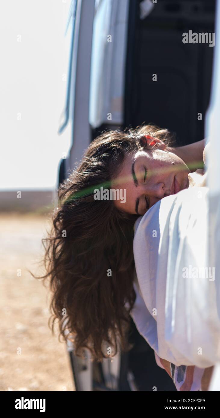 Vertical shot of a young female hanging hair out a car window and ...