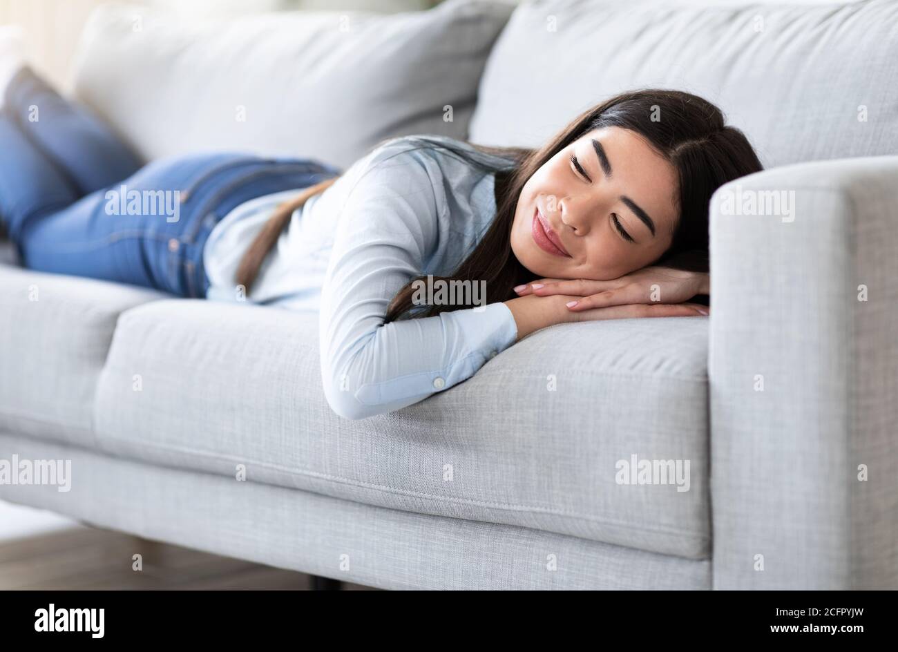 Lazy Day At Home. Relaxed Asian Girl Enjoying Lying On Comfortable Sofa Stock Photo