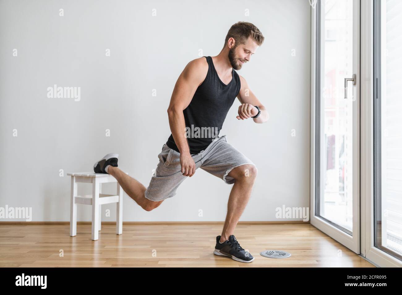 Handsome young man working out at home with a smart watch Stock Photo