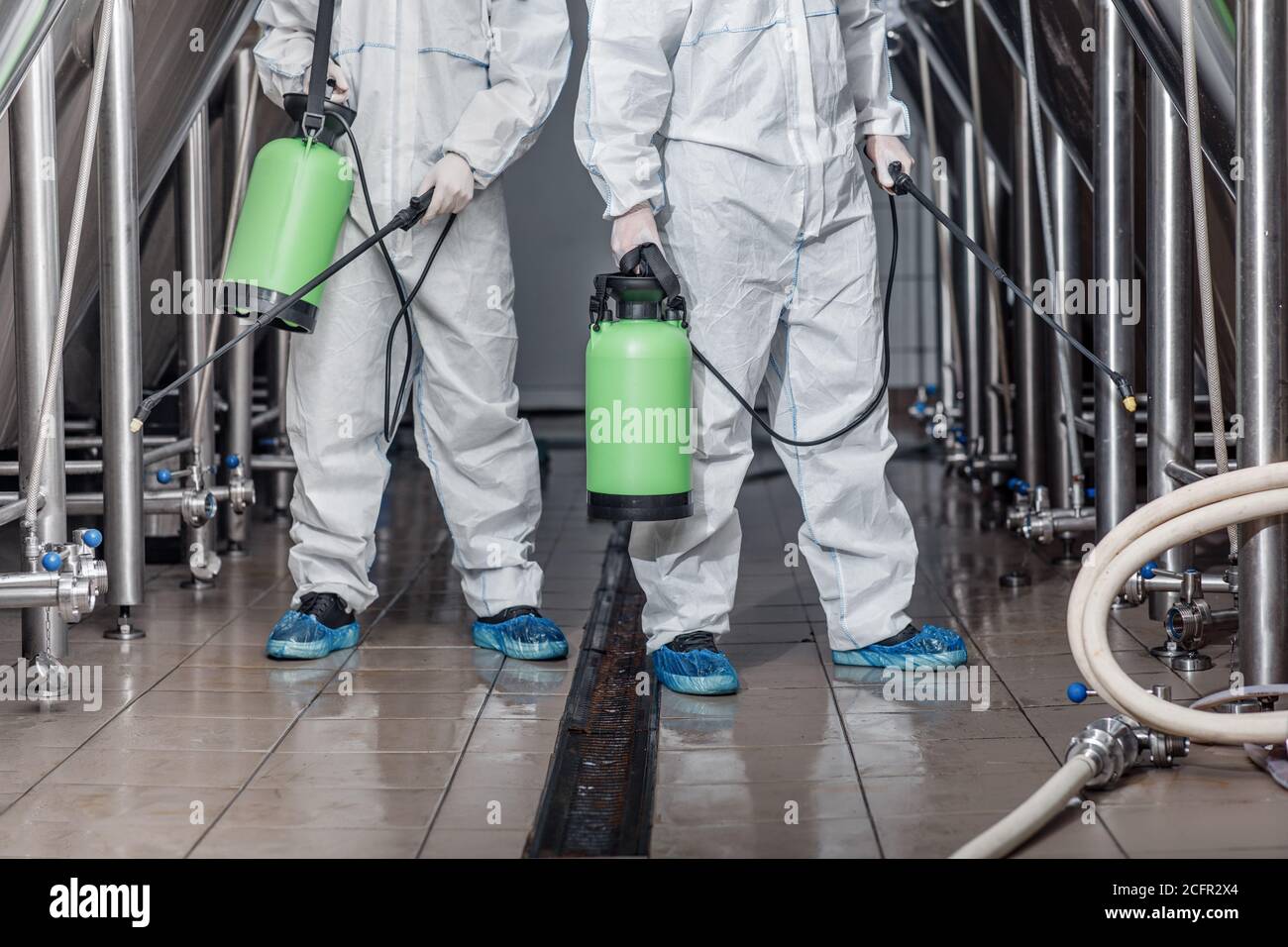 Cleaning of production. Guys in hazmat suits disinfect equipment Stock