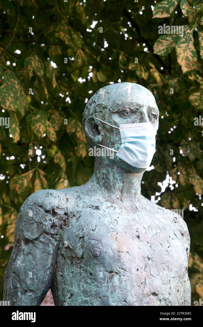 A detail of The Dorset Martyrs sculpture by Dame Elizabeth Frink, showing a statue wearing a surgical face mask during the Covid 19 pandemic. England. Stock Photo