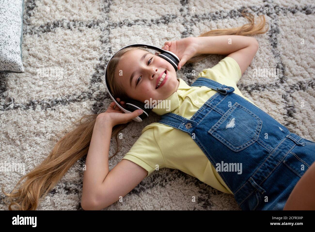 Teenager listening to music lying on carpet Stock Photo - Alamy