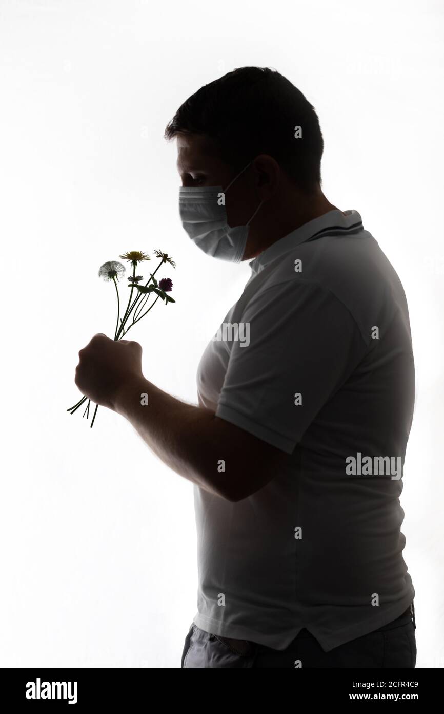 man with face mask smell the meadow flowers Stock Photo