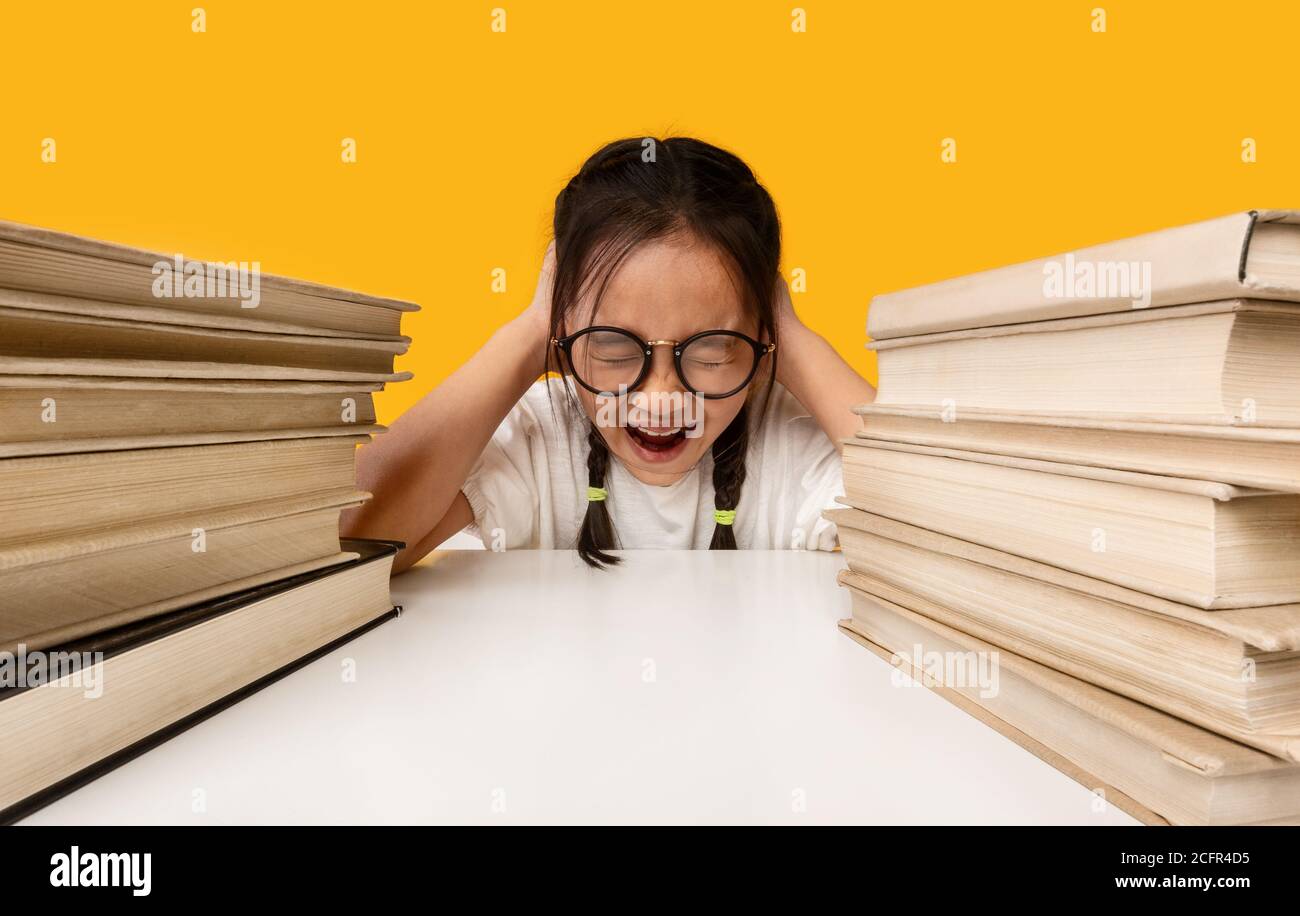 Unhappy Asian Schoolgirl Crying Sitting At Books, Studio Shot Stock Photo