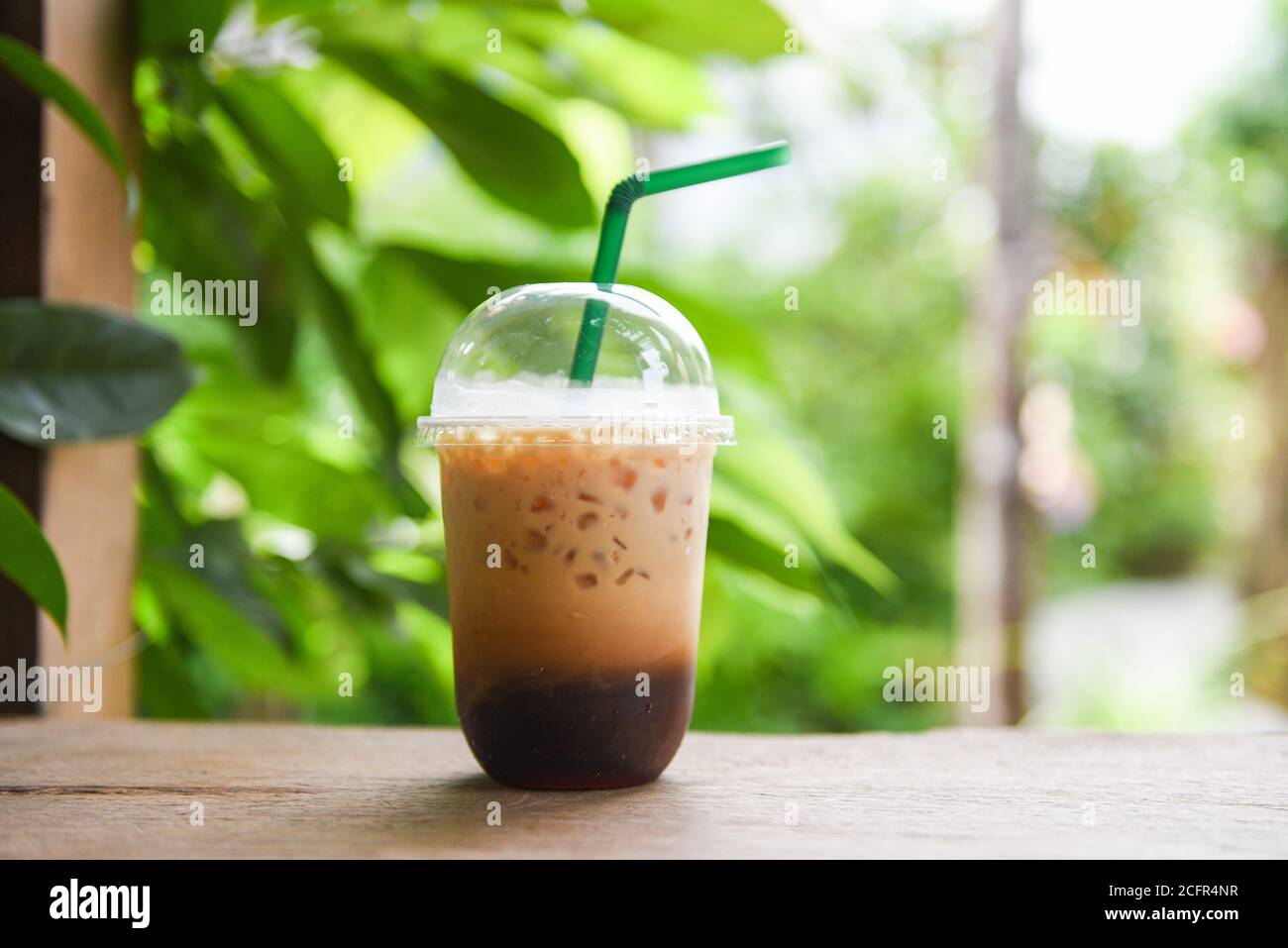 https://c8.alamy.com/comp/2CFR4NR/iced-coffee-latte-in-plastic-cup-on-wooden-table-and-nature-green-background-iced-drinks-2CFR4NR.jpg