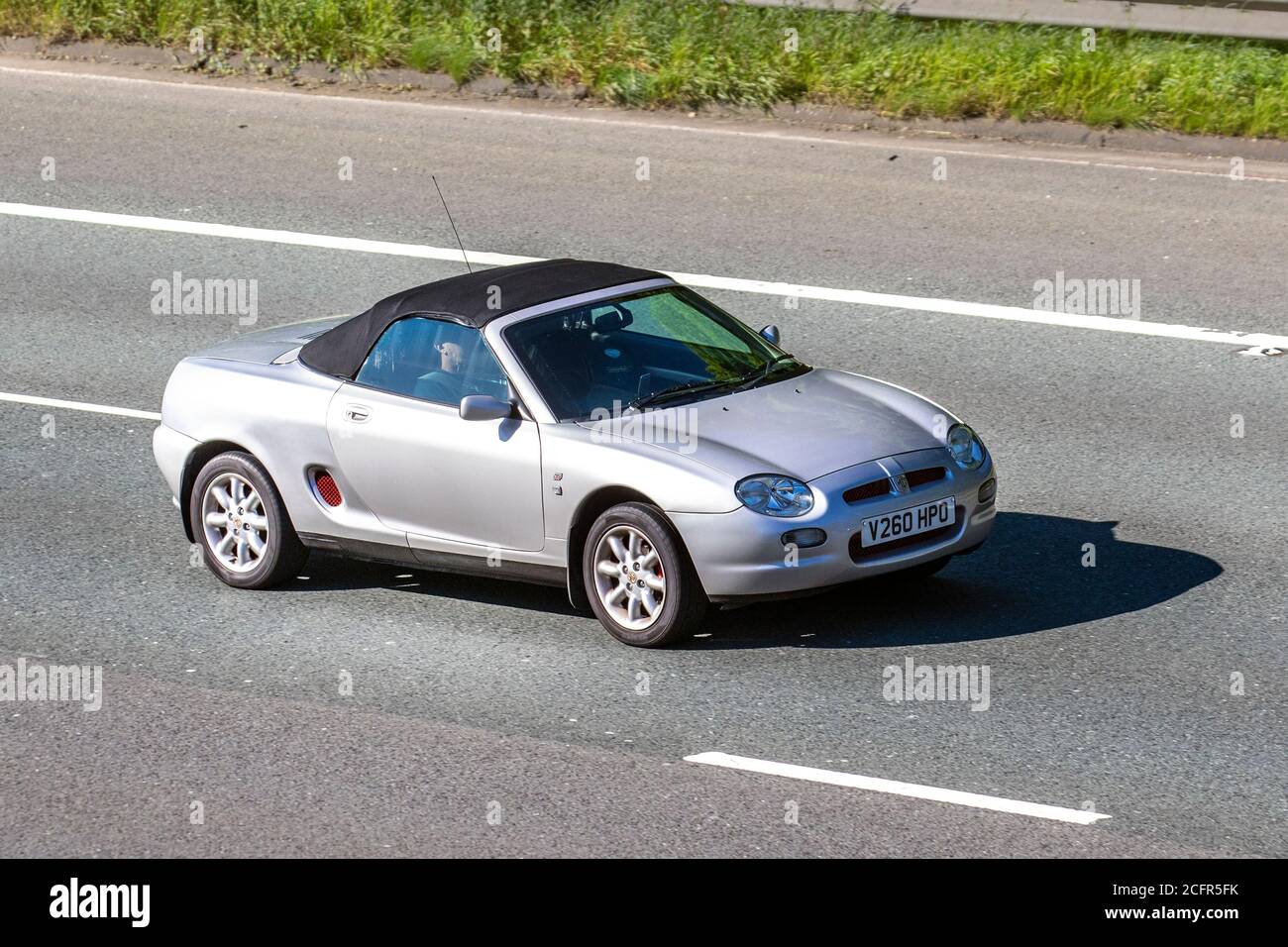 2000 silver 2dr MG MGF roadster ; Vehicular traffic moving vehicles, cars driving vehicle on UK roads, motors, motoring on the M6 motorway highway network. Stock Photo