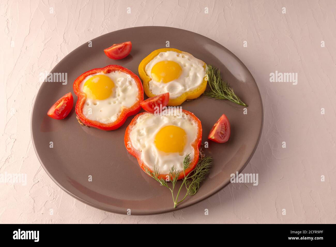 Scrambled eggs fried in rings of Bulgarian pepper with tomatoes and herbs. Stock Photo