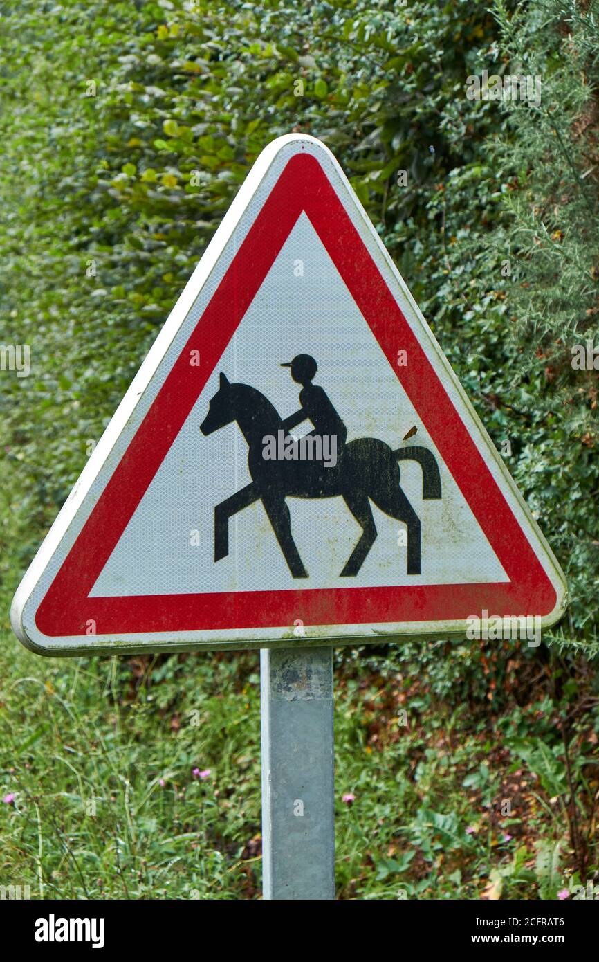 French triangular metal warning sign portraying a trotting horse and rider Stock Photo