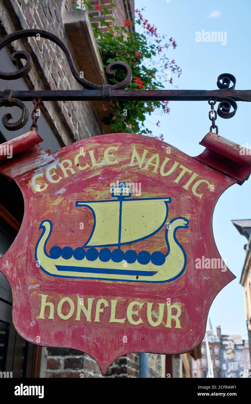 Red coloured french metal nautical hanging sign of the Honfleur Harbour Office with illustration of a Viking boat. Stock Photo