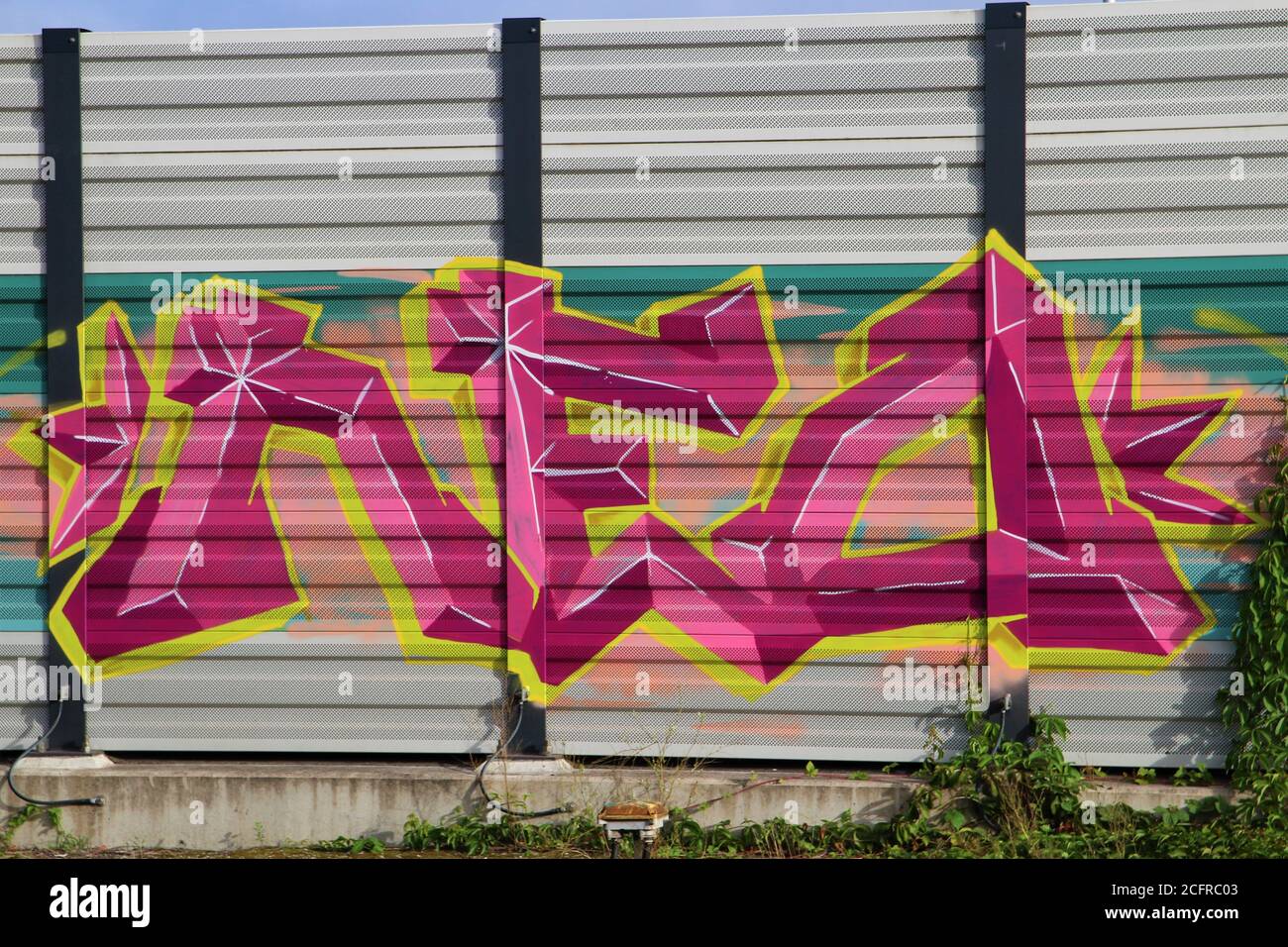 Purple,yellow and pink graffiti on a noise barrier wall Stock Photo