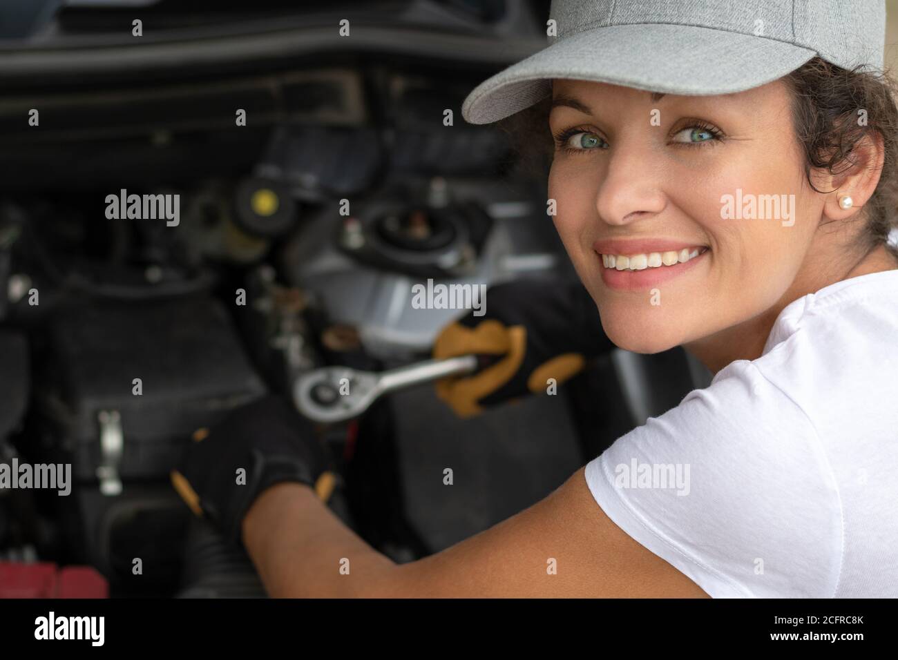 Woman work power. Female auto mechanic worker on car engine using a