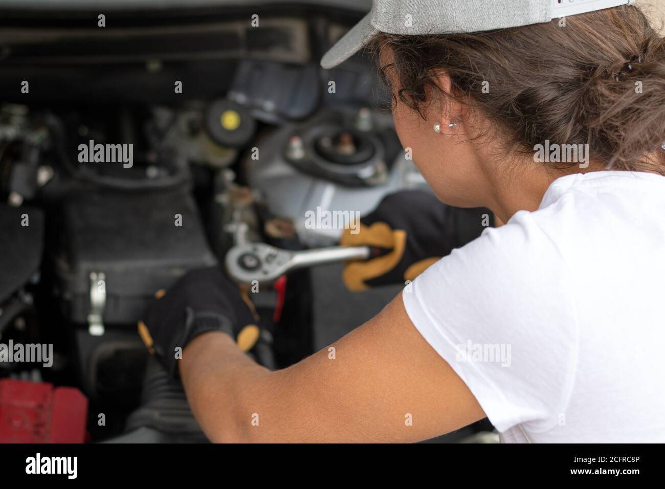 Woman work power. Female auto mechanic worker on car engine using a ratchet. Repair service. Authentic close-up shot. Labor day. Stock Photo