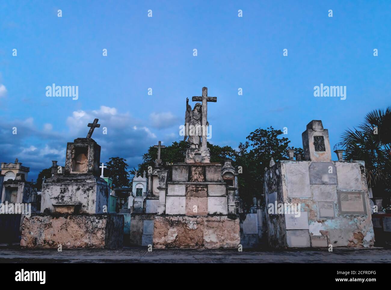Old graveyard tombs with corsses and angel statue during blue lighted ...