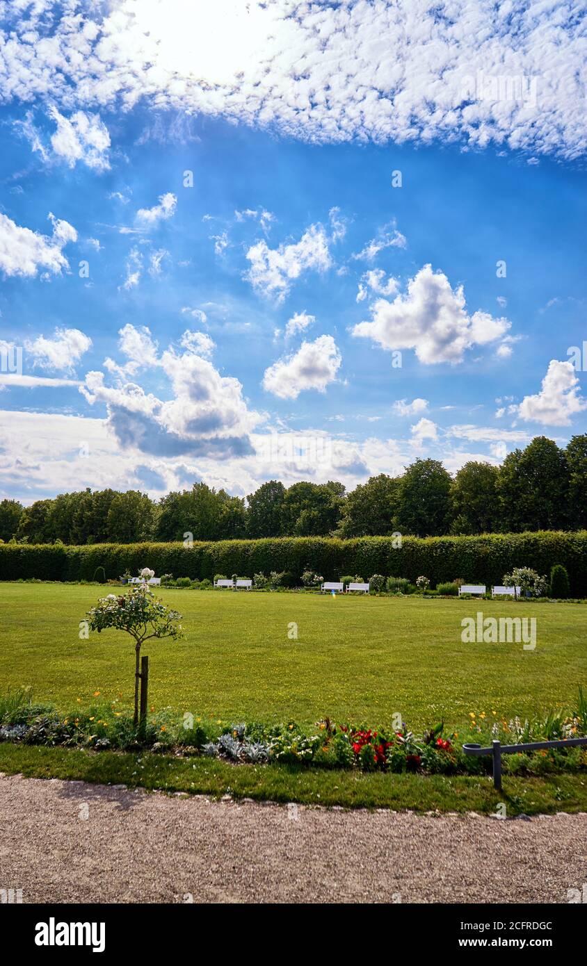 Park benches under a blue sky with sun and white clouds Stock Photo - Alamy
