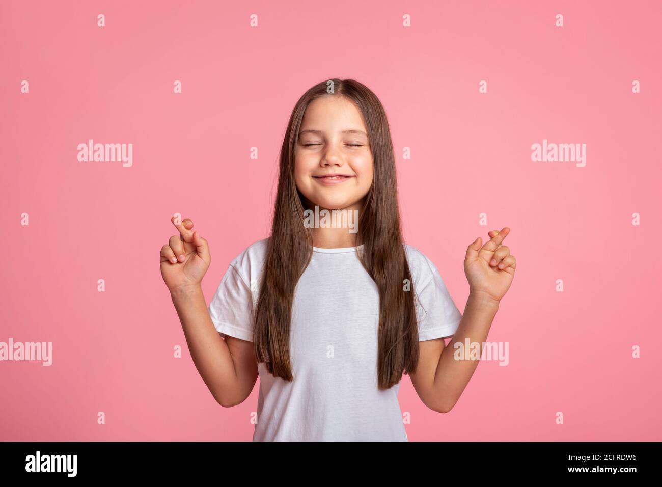 Smiling child with closed eyes and crossed fingers makes wish Stock Photo