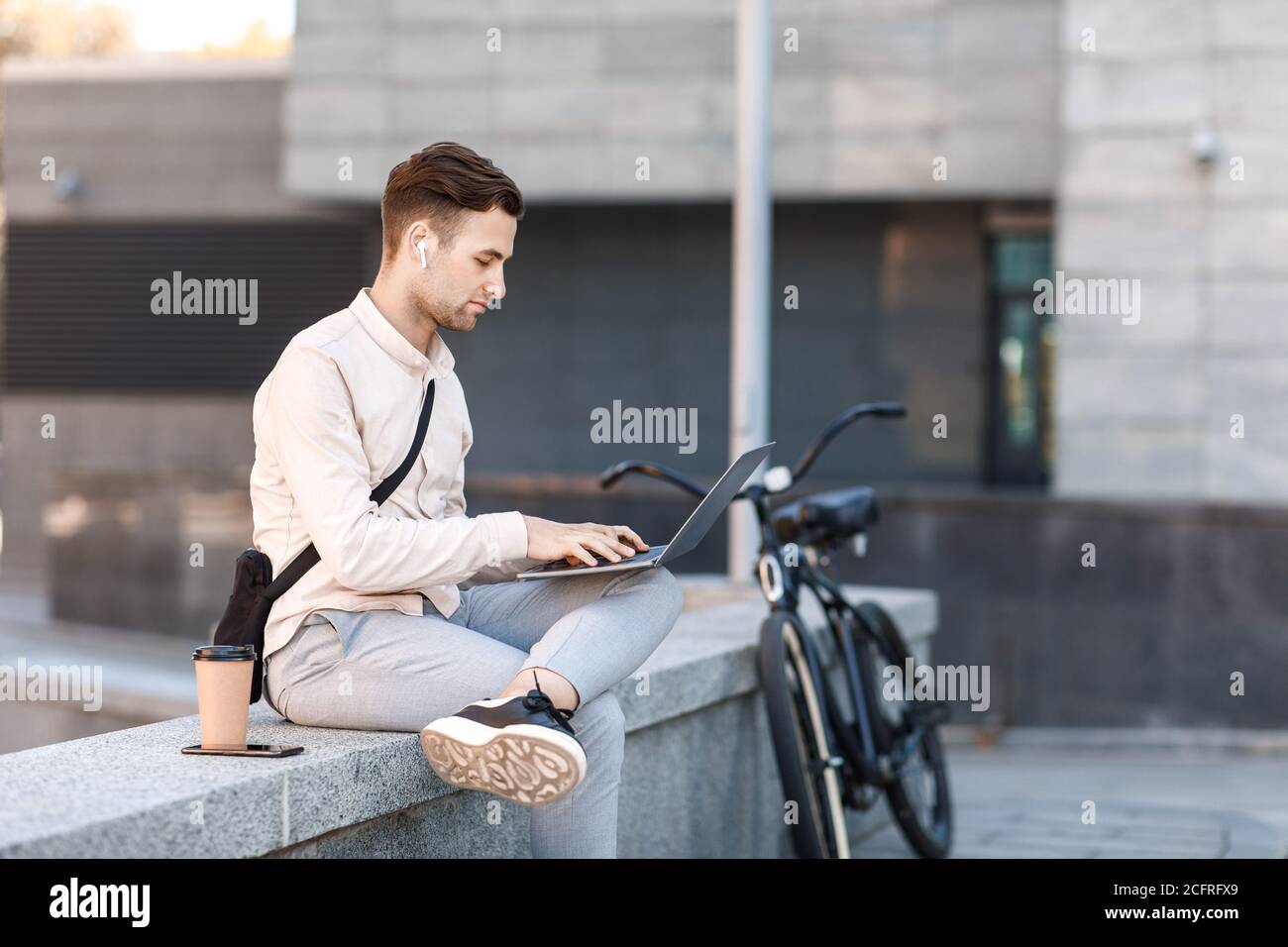 Office online outdoor. Busy man working on laptop with wireless headphones Stock Photo