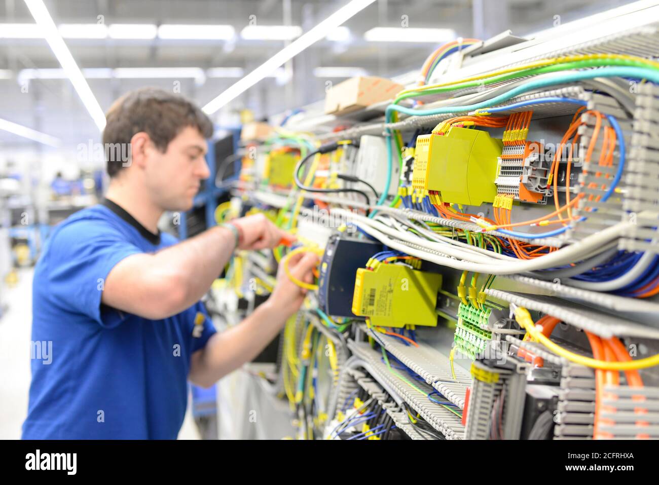 man assembles electronic components on a machine in a factory for mechanical engineering Stock Photo