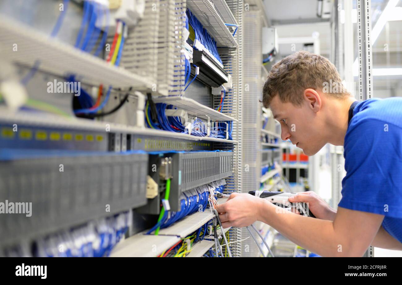 young apprentice worker in an industrial company assembling electronic ...