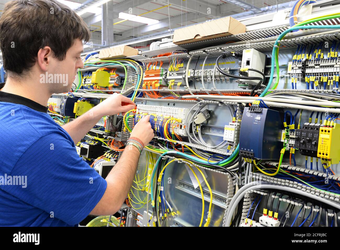 young operator assembles machine in a modern high tech factory - production of switch cabinets for industrial plant Stock Photo