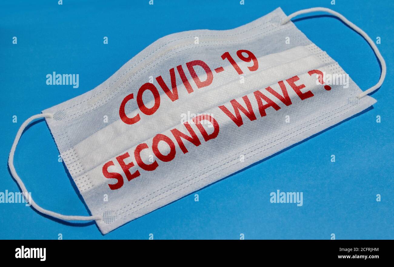 Medical face mask with COVID-19 SECOND WAVE text on blue background. Concept of coronavirus quarantine. Stock Photo