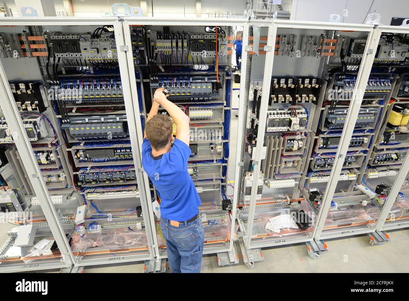 young apprentice assembles components and cables in a factory in a switch cabinet - workplace industry with future Stock Photo