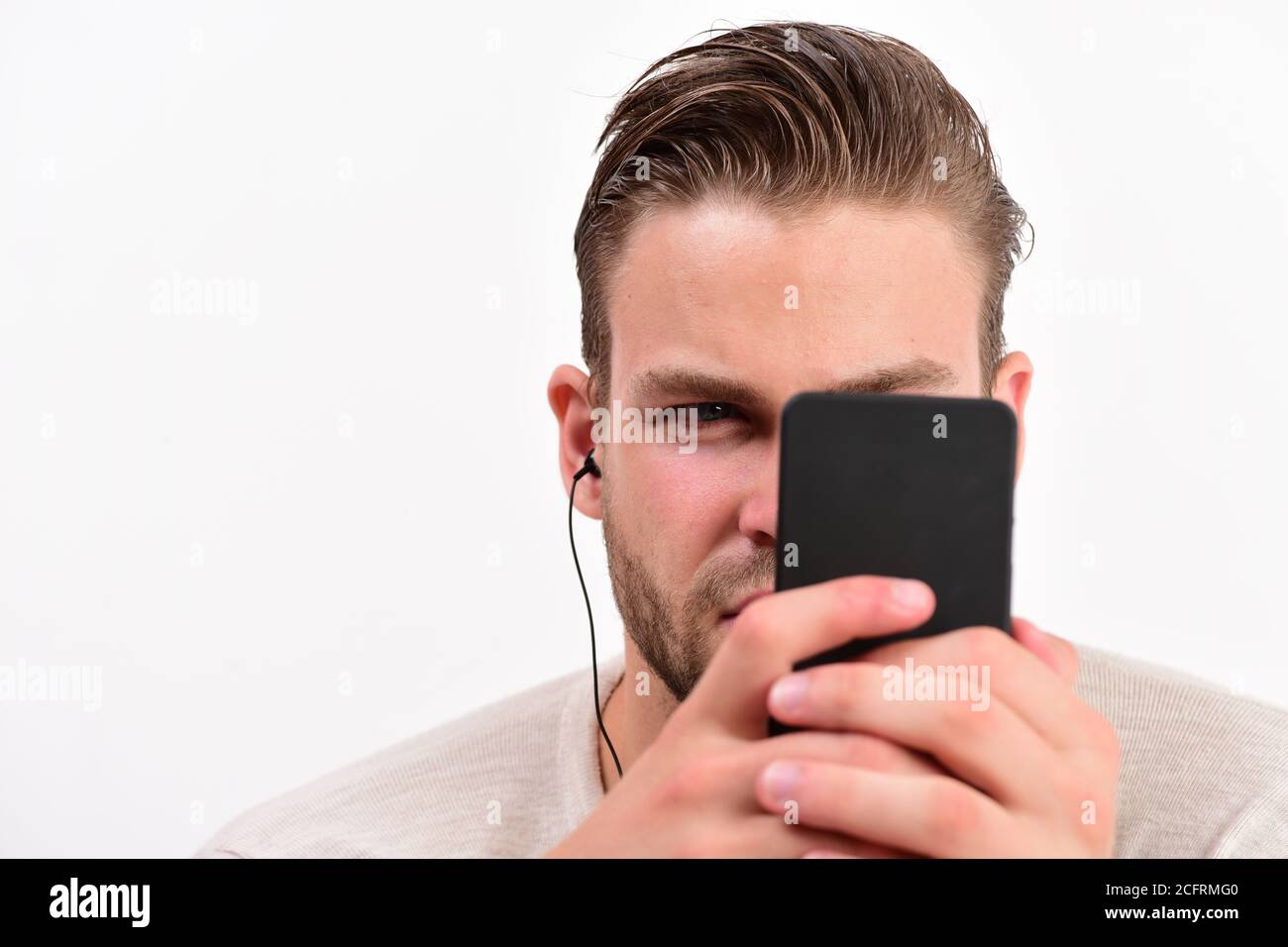 man-with-attentive-face-looks-at-mobile-phone-entertainment-and-musical-lifestyle-concept-guy-with-beard-holds-mp3-player-and-wears-earphones-on-white-background-macho-with-headphones-watches-video-2CFRMG0.jpg